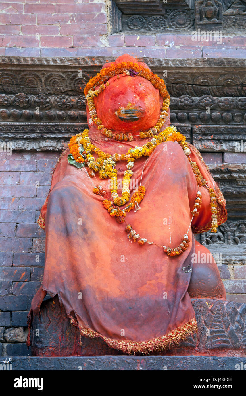 Statuetta di un dio coperto in una copertura di colore arancione e adornata con collane di Le calendule, Patan Durbar Square, Patan o Lalitpur Kathmandu in Nepal Foto Stock