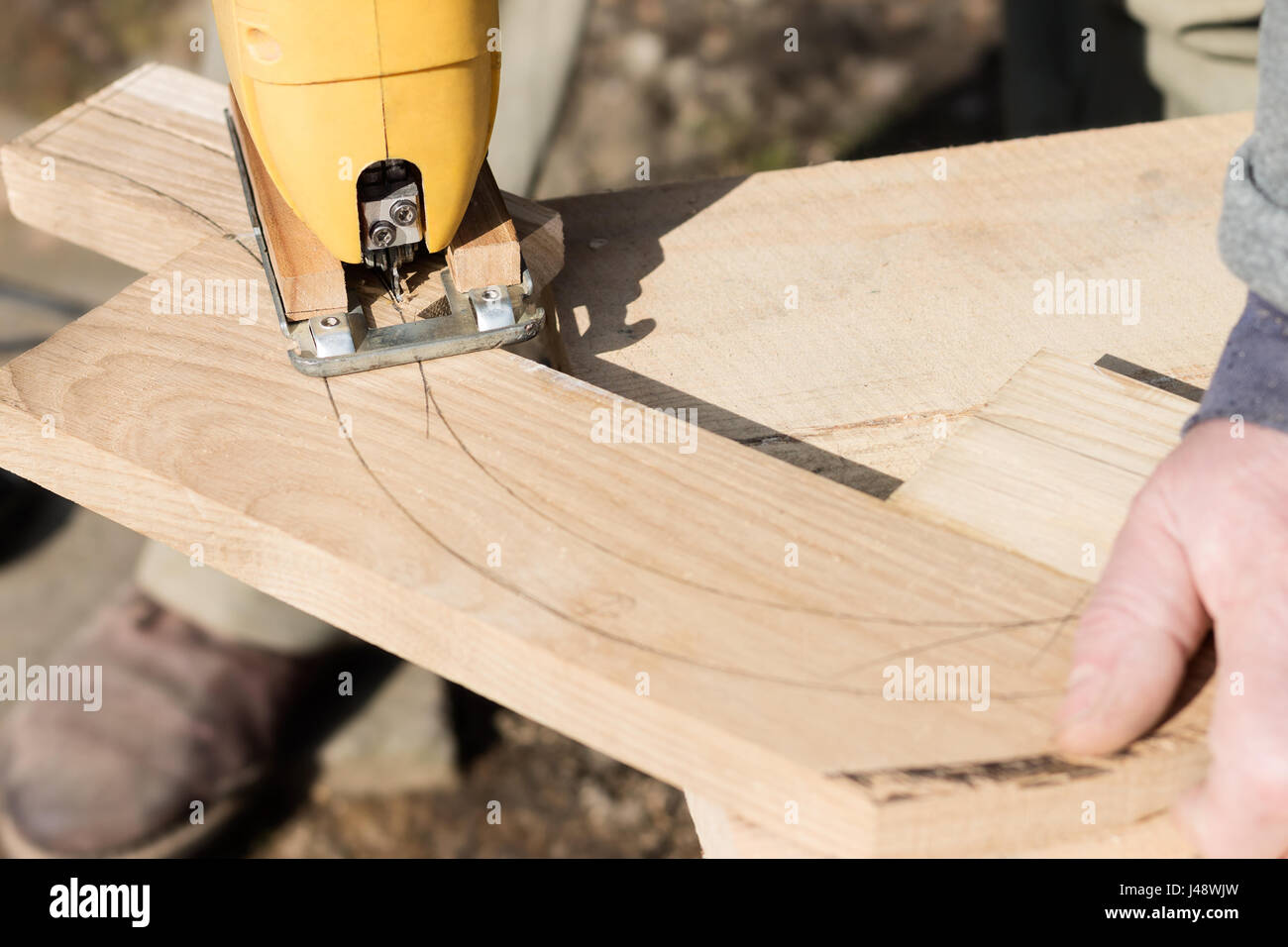 Falegname è il taglio di una forma ad arco dalla tavola di legno con Seghetto da traforo. Fabbricazione di mobili. Foto Stock
