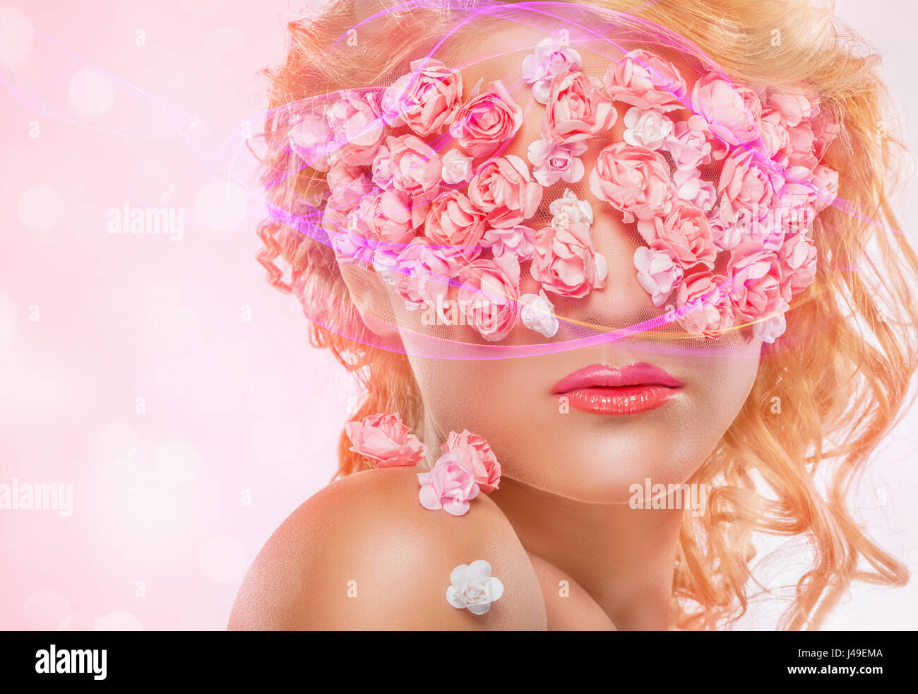 Giovane bella ragazza bionda con il trucco di moda e fiori di colore rosa. Bokeh di fondo Foto Stock