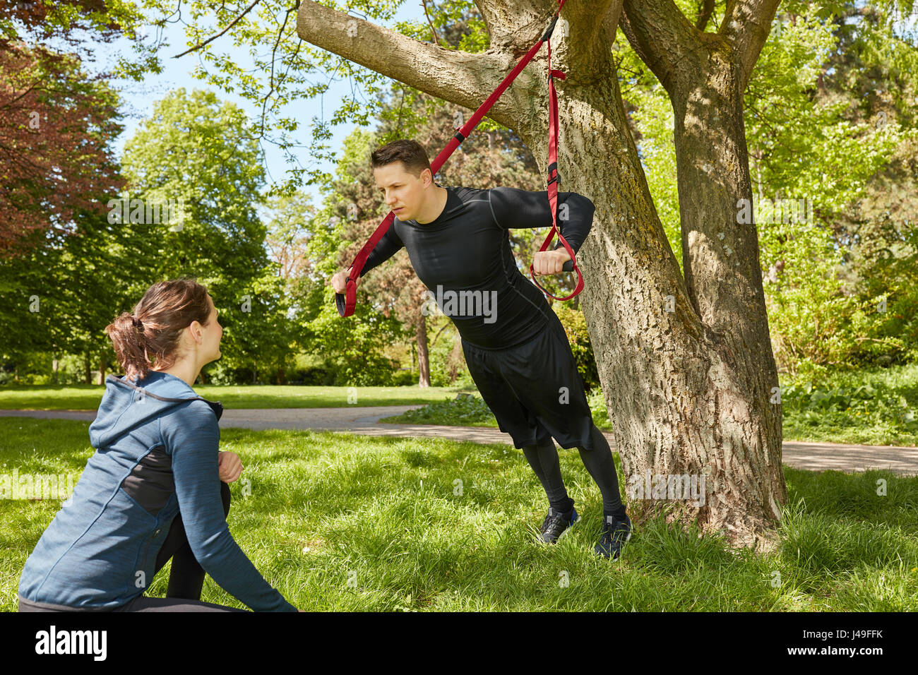 Formazione di sospensione nel parco con personal trainer Foto Stock