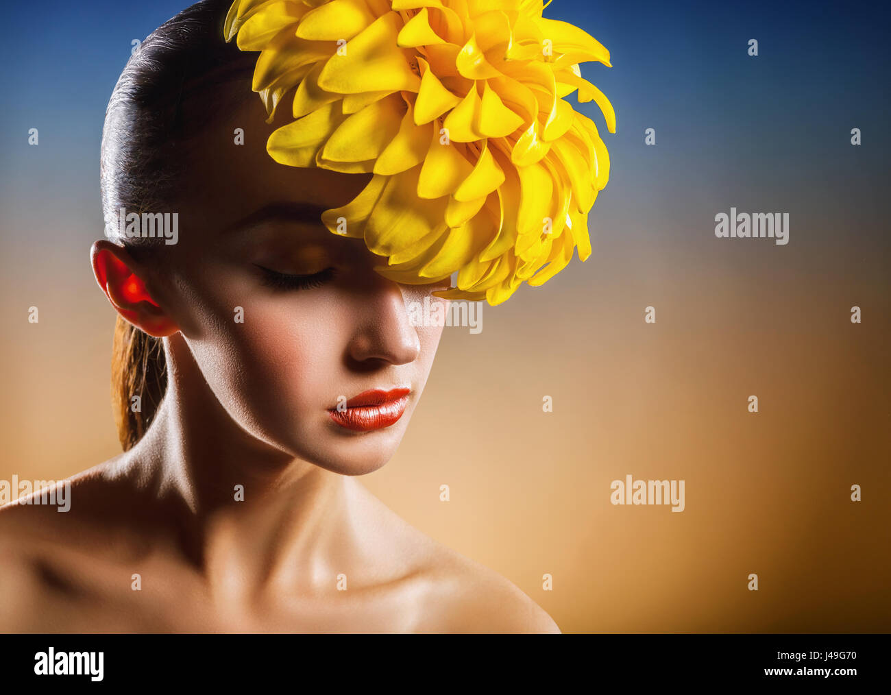 Ritratto di una bellissima ragazza con un fiore giallo dei capelli. Modello di moda Foto Stock
