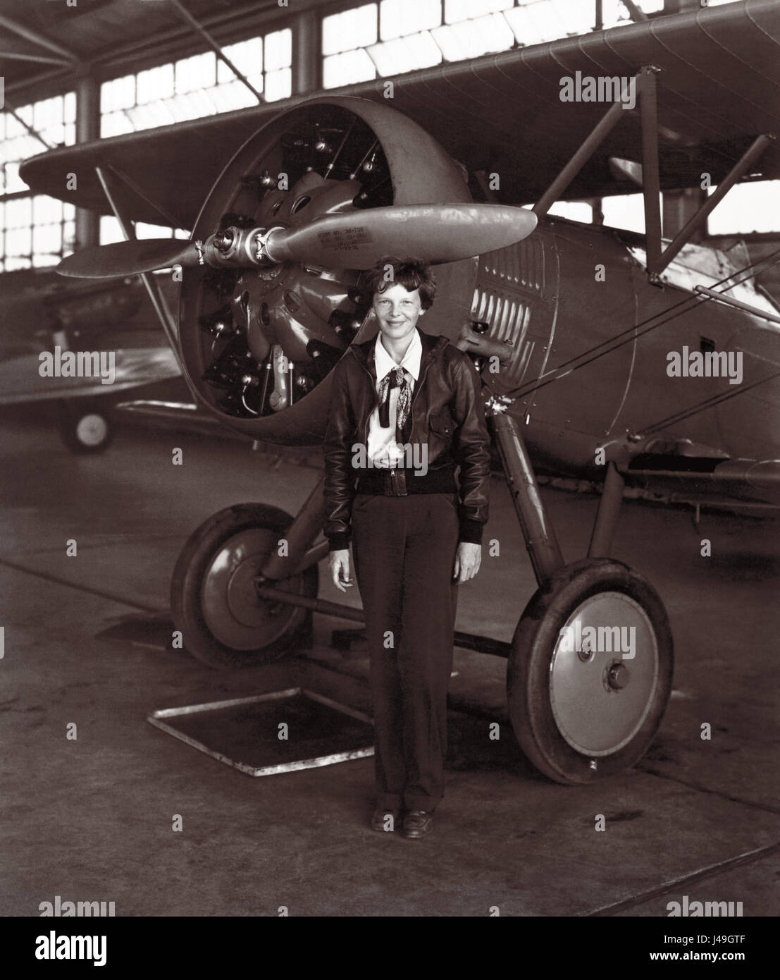 Amelia Earhart, la prima donna ad effettuare un volo solo attraverso l'Oceano Atlantico, in piedi di fronte a un biplano sulla luglio 30, 1936, quasi un anno dopo la sua scomparsa oltre l'Oceano Pacifico ai primi di luglio del 1937. Foto Stock