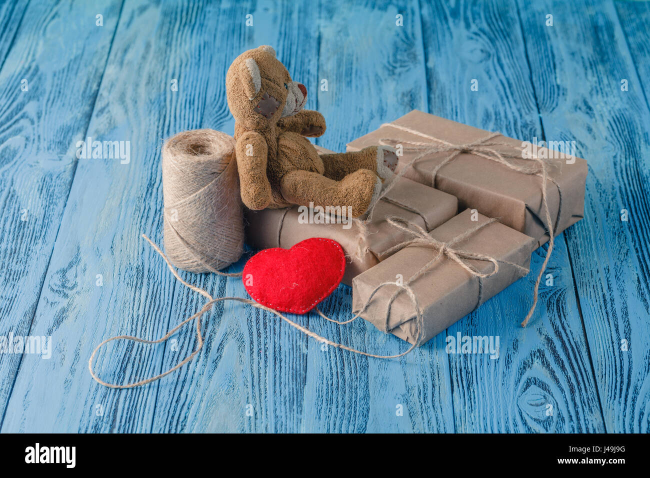 Toy orso e alcuni pacchi in carta avvolta su un tavolo di legno. In stile vintage. Foto Stock
