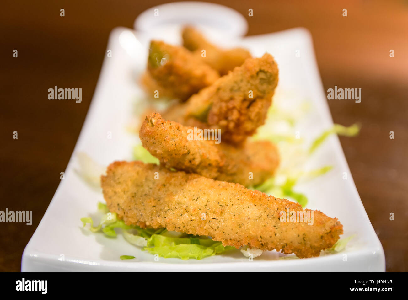 Deliziosa dill pickle spears con casa fatta pastella, caldo e pronto a dip. Servita su una piastra bianca con ranch dressing. Foto Stock