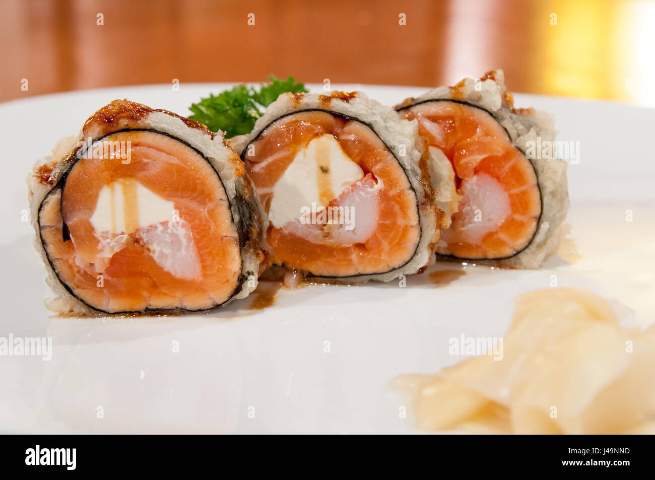 Un profondo fritto rotolo di sushi con salmone, granchi e crema di formaggio, sauced leggermente. Arrotolata senza il riso. Foto Stock