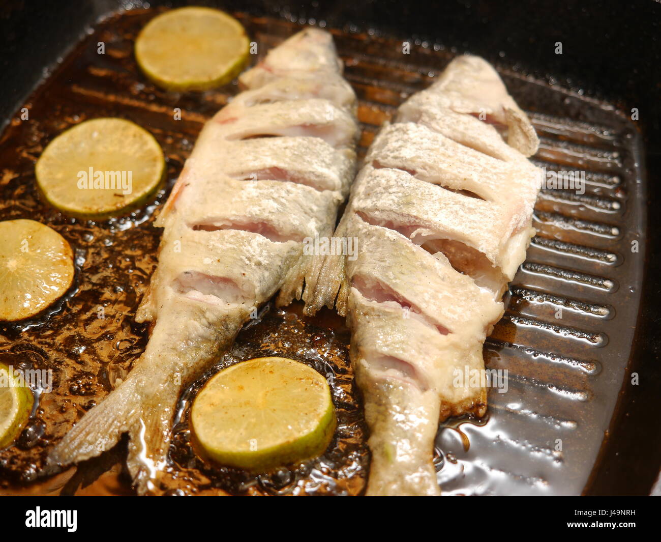 La frittura di pesce tagliato in una padella con il limone Foto Stock