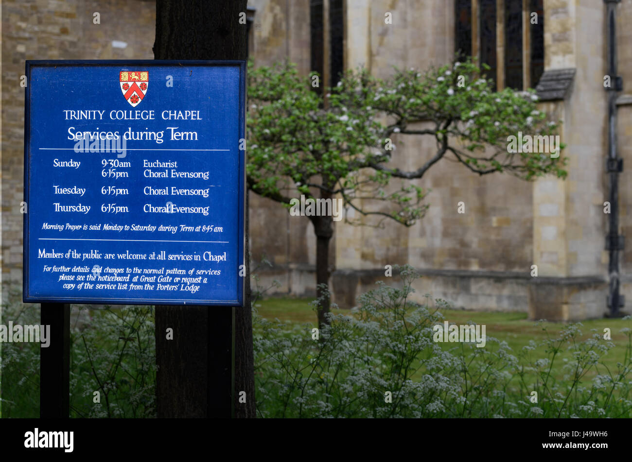 Avviso sul prato anteriore circa i tempi di servizio nella cappella del Trinity College dell'università di Cambridge, Inghilterra, Gran Bretagna. Foto Stock