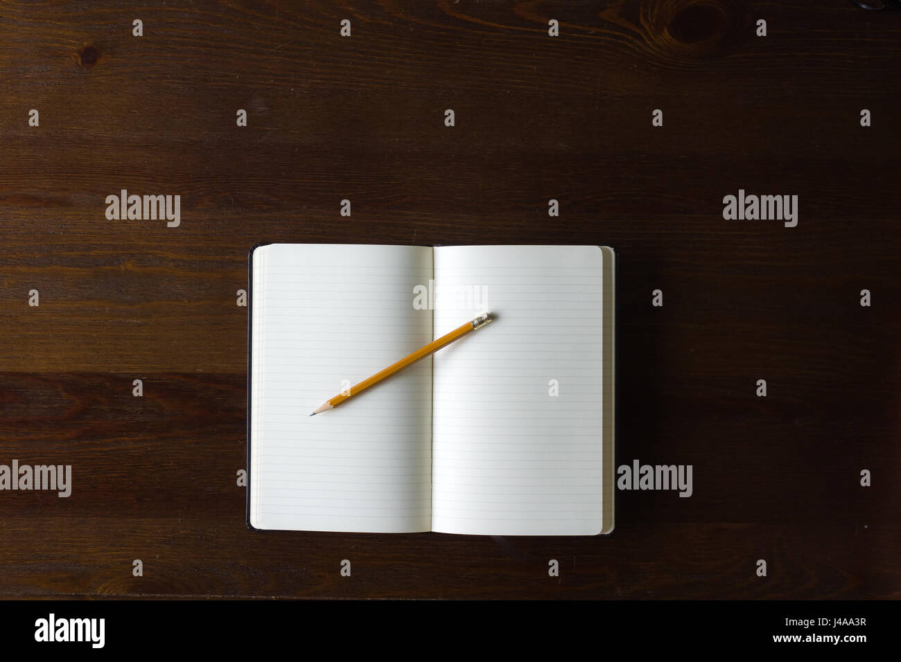 Un notebook bianco e matita su una tavola di legno, con copia spazio. Foto Stock