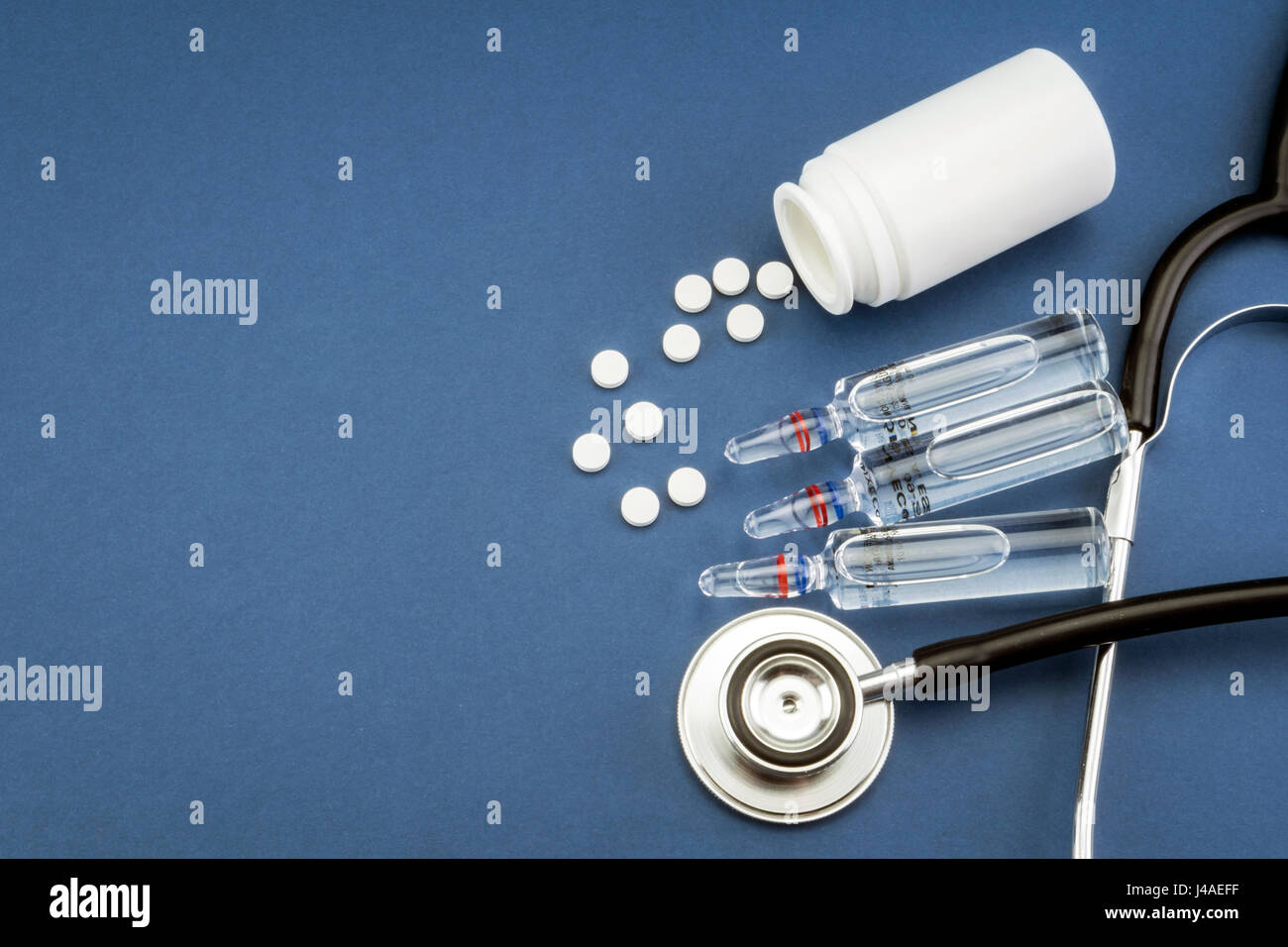 Stetoscopio, pillole, fiale in sala medica su sfondo blu top view mockup Foto Stock