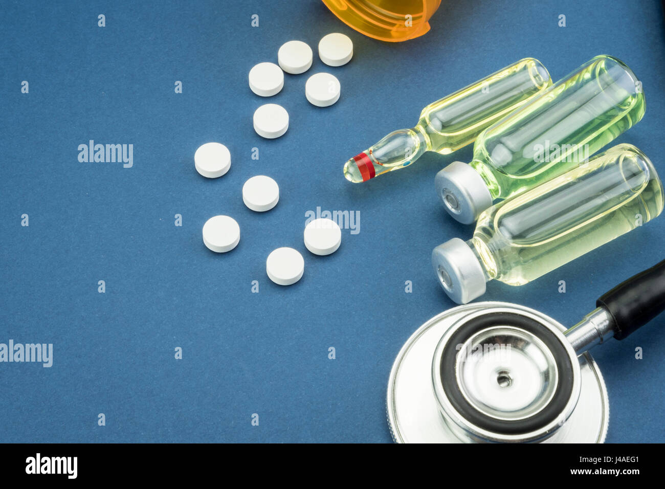 Stetoscopio, pillole, fiale in sala medica su sfondo blu Foto Stock