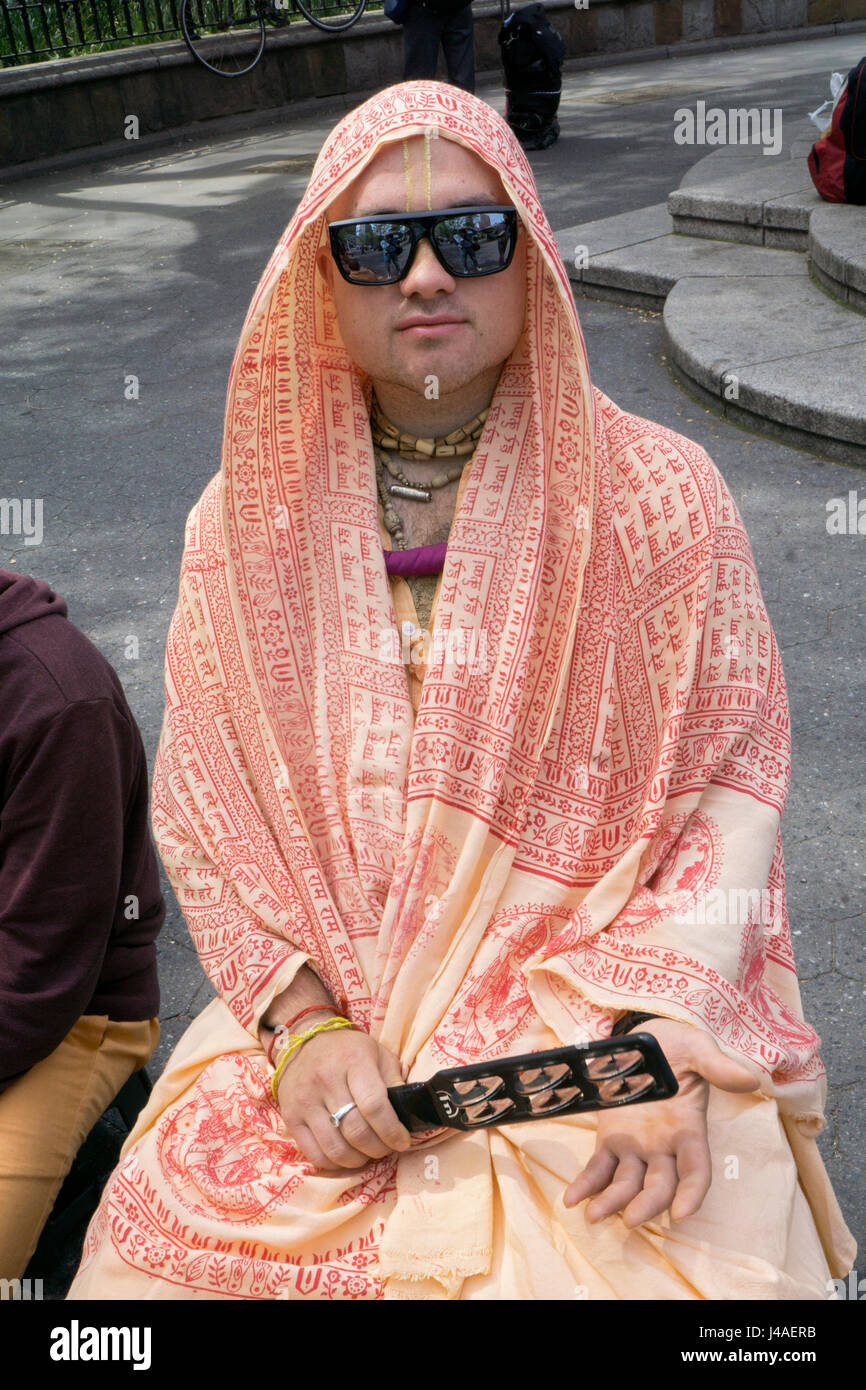 Hare Krisna devoto in hipster occhiali da sole a suonare le percussioni in Union Square Park a Manhattan, New York City Foto Stock