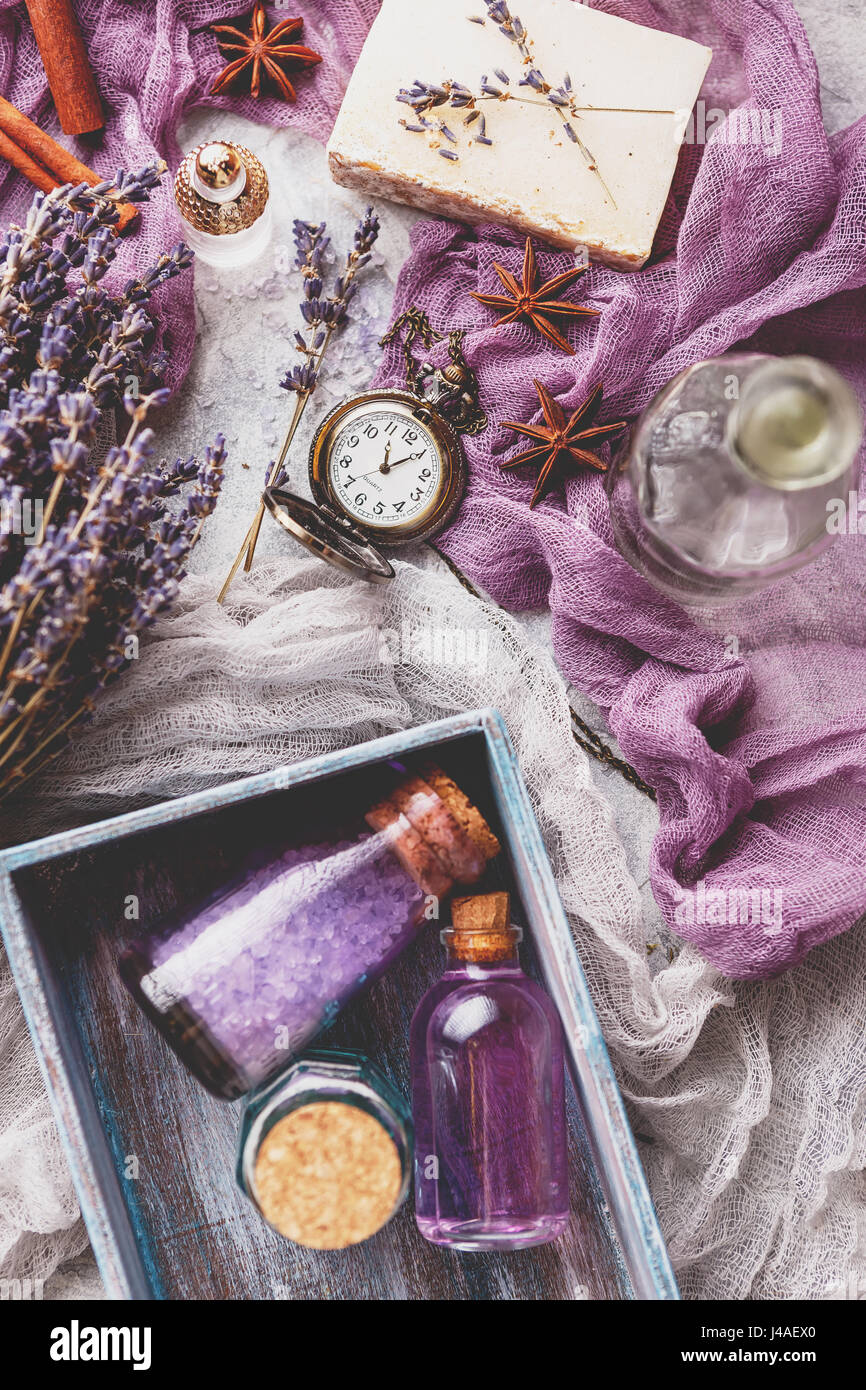 Bottiglia aromatico con olio di lavanda e sale marino in una scatola di legno, una bottiglia di profumo, un bouquet di fiori di lavanda e un pezzo di sapone e un vintage orologio da tasca. Foto Stock