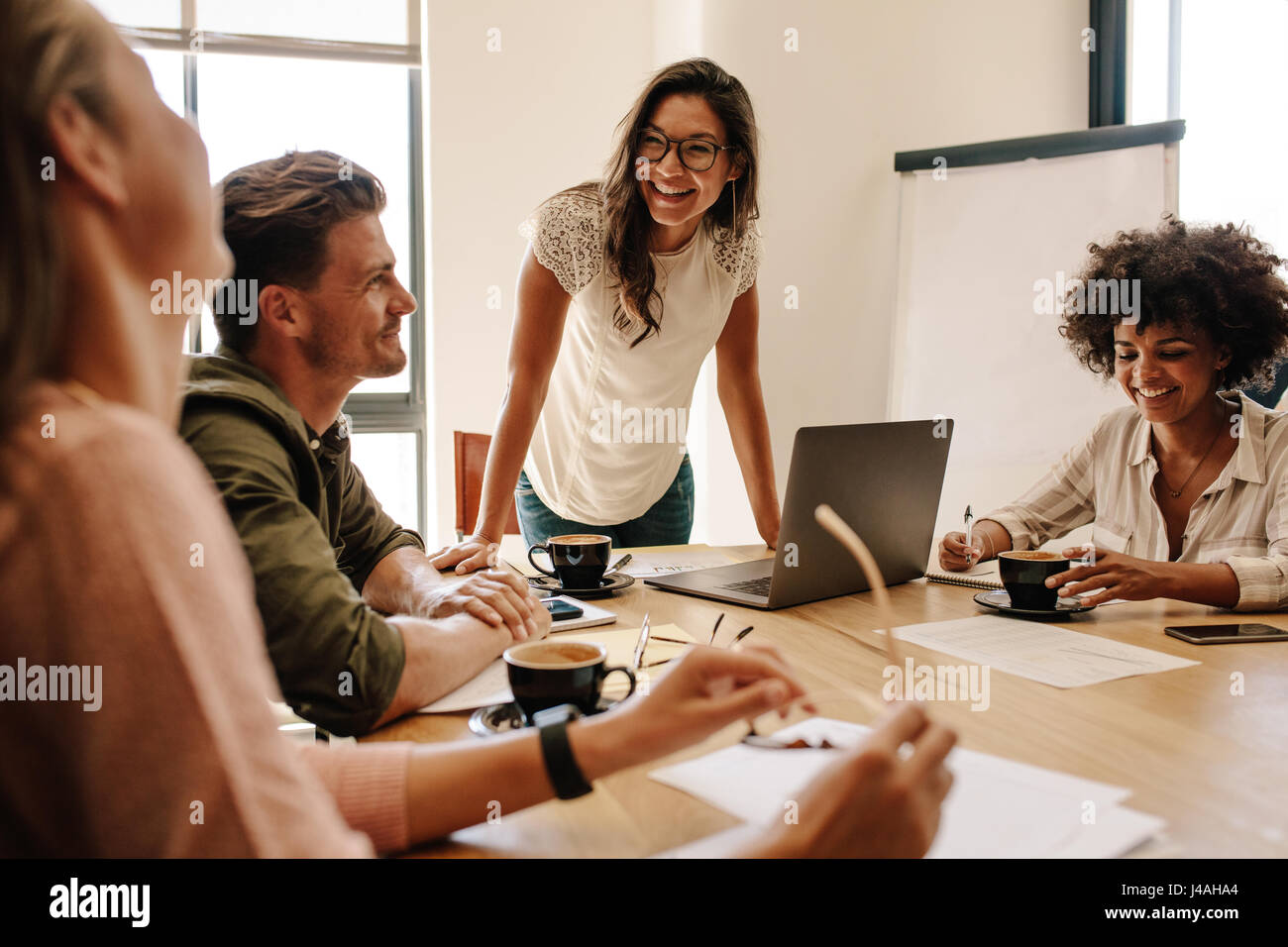 Gruppo di multi etnico discutendo i dirigenti durante una riunione. Uomo di affari e donna seduta intorno al tavolo in ufficio e sorridente. Foto Stock