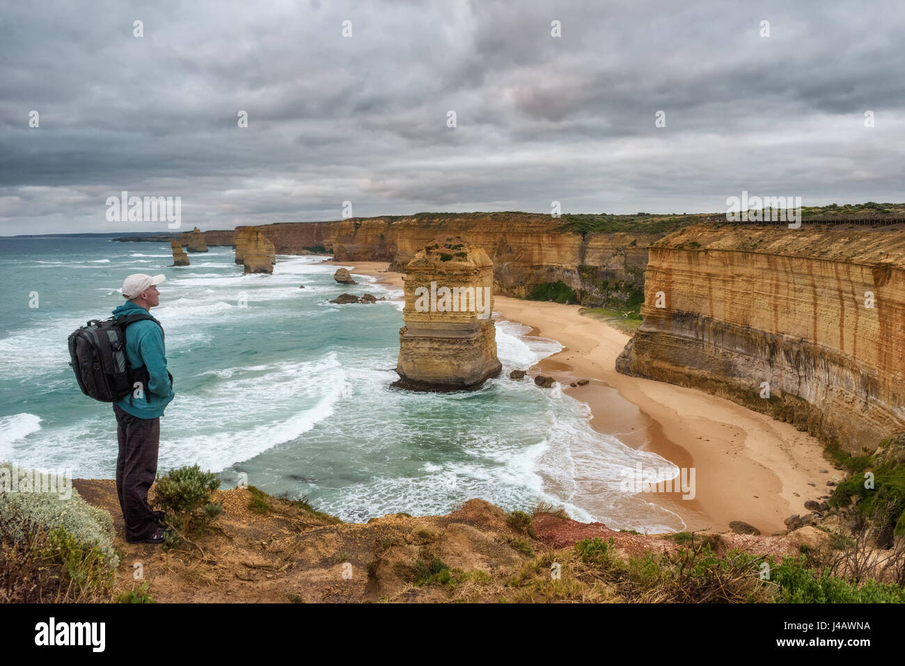 Giovane escursionista si erge sopra i dodici Apostoli lungo la famosa Great Ocean Road in Victoria, Australia, vicino a Port Campbell. Foto Stock