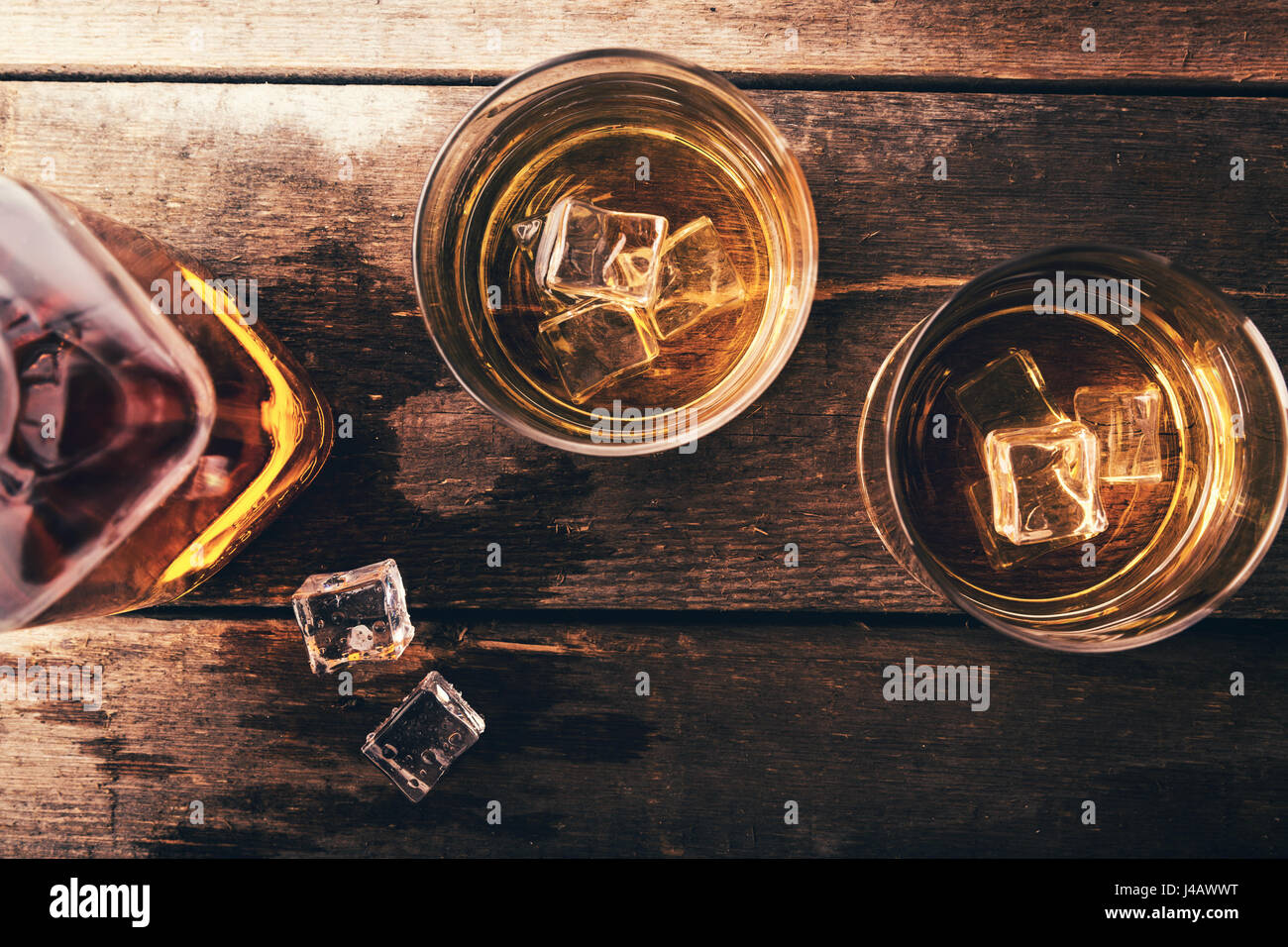 Il whiskey con ghiaccio sul vecchio legno scuro tavolo. vista superiore Foto Stock