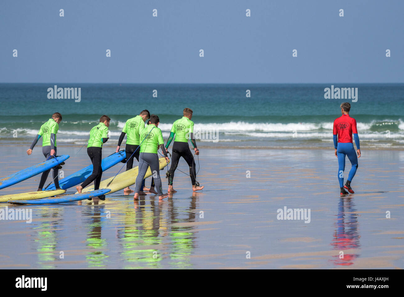 Una scuola di surf istruttore leader di un gruppo di novizi di surf su Fistral Beach Foto Stock