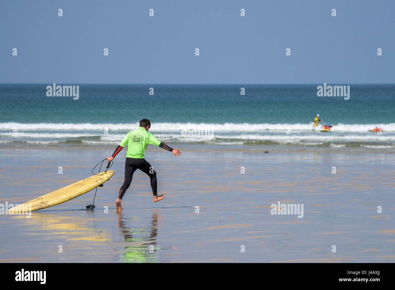 Un entusiasta scuola surf novizio corre al mare; fuga Scuola Surf; Fistral Beach;, Newquay Cornwall; Surf; Surfer; Studente; apprendimento Foto Stock