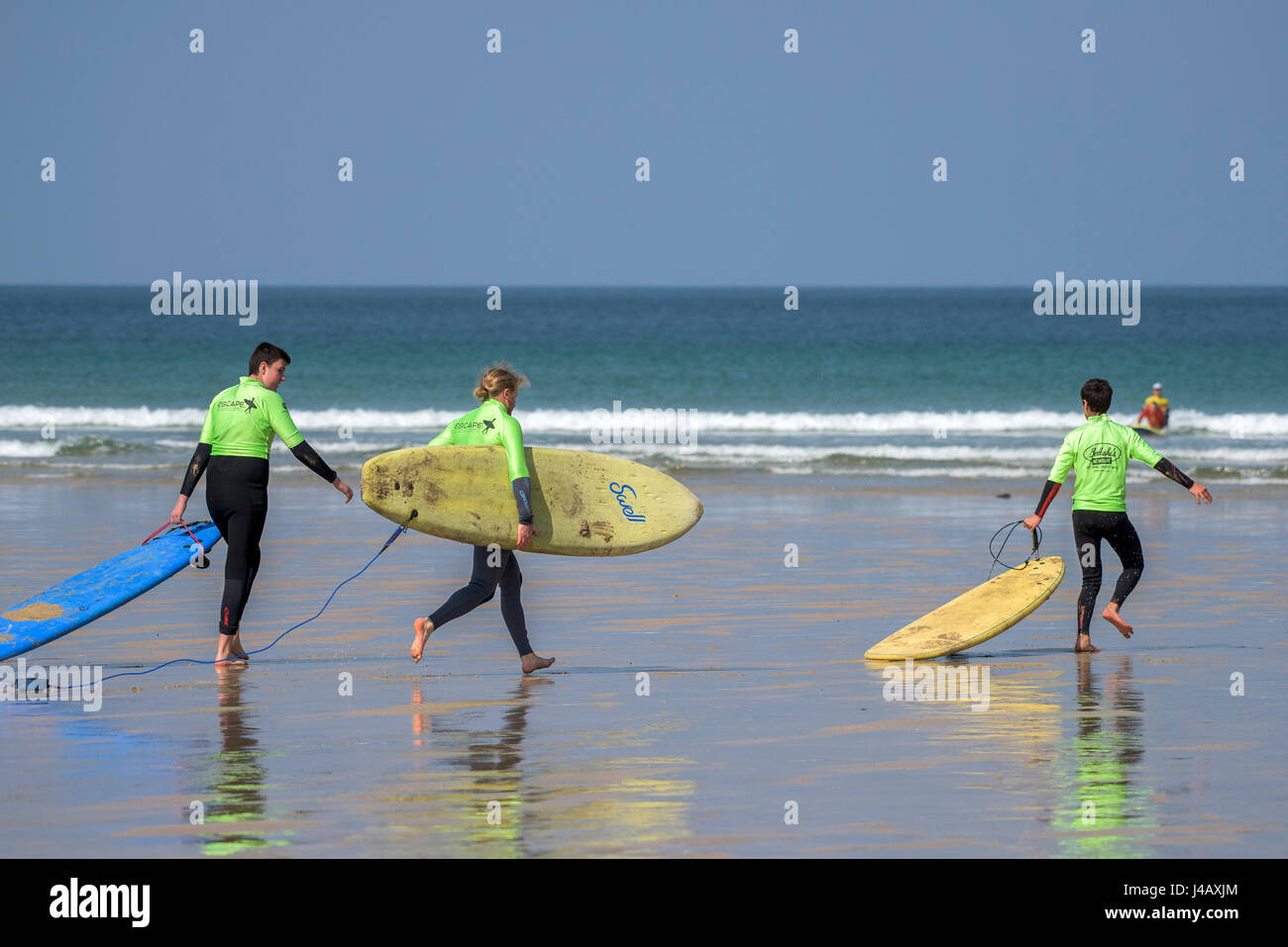 Entusiasta della scuola di surf novizi di corsa in mare fuga Scuola Surf Fistral Beach Newquay Cornwall Surf Surfers allievi desiderosi di apprendimento Foto Stock