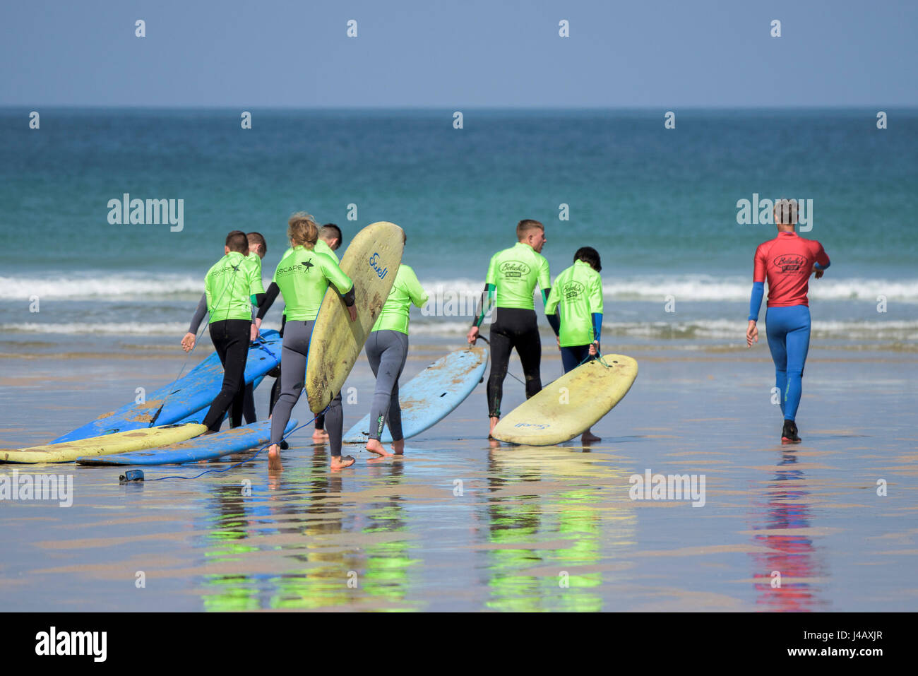 Una scuola di surf istruttore è a capo di un gruppo di novizi di surf fuga Scuola Surf Fistral Beach Newquay Cornwall Surf Surfers ai partecipanti Foto Stock