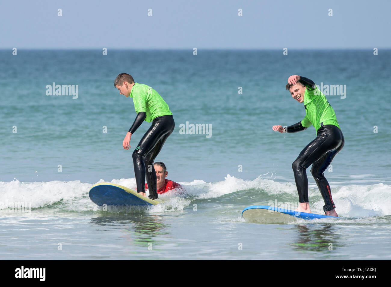 Novizi ad imparare a navigare su Fistral Beach in Newquay Cornwall fuga Scuola Surf Surf Surfers partecipanti istruttore di apprendimento aiutando Mare Foto Stock