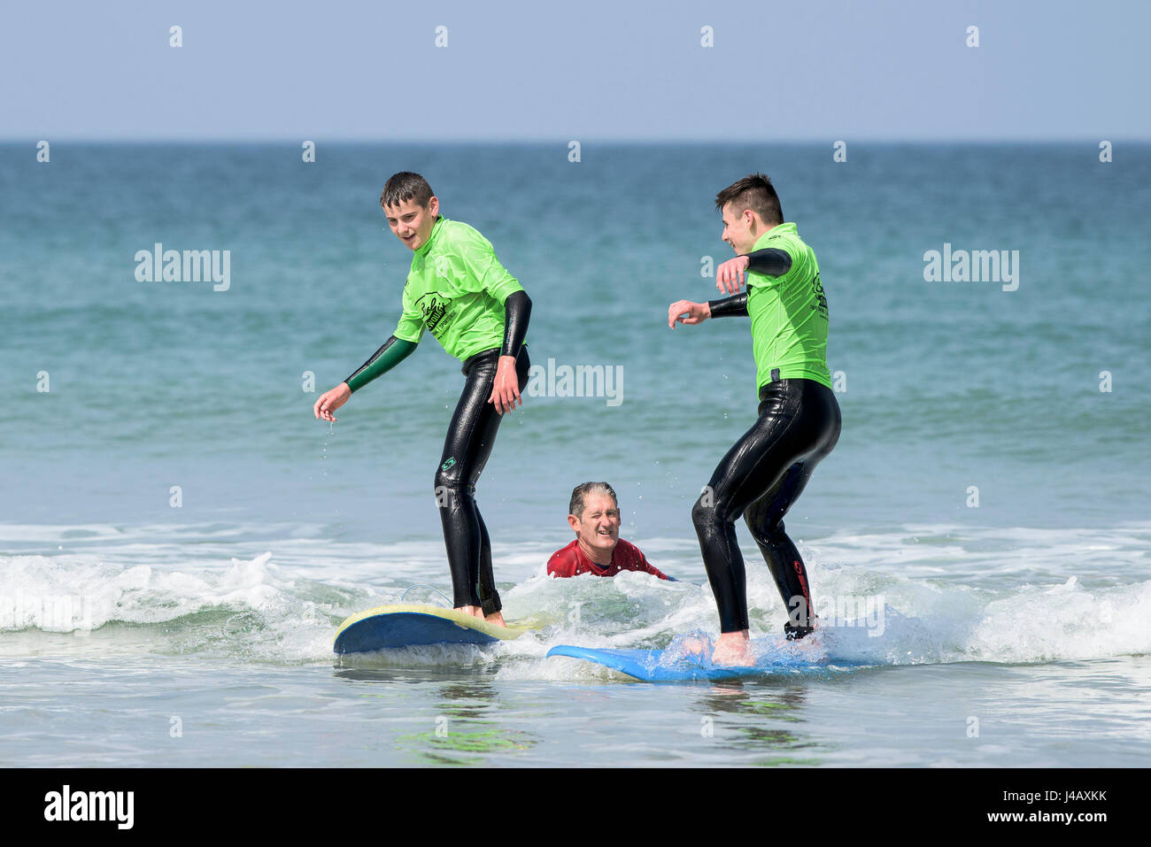 Novizi ad imparare a navigare su Fistral Beach in Newquay Cornwall fuga Scuola Surf Surf Surfers partecipanti istruttore di apprendimento aiutando Mare Foto Stock