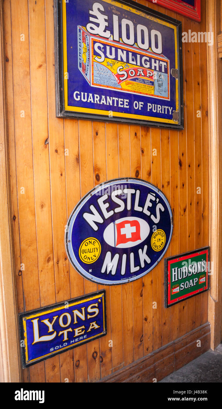 Vecchi segni sulla parete in un negozio presso il museo Beamish,l'Inghilterra,UK. Si accoccola latte,sapone alla luce solare Foto Stock