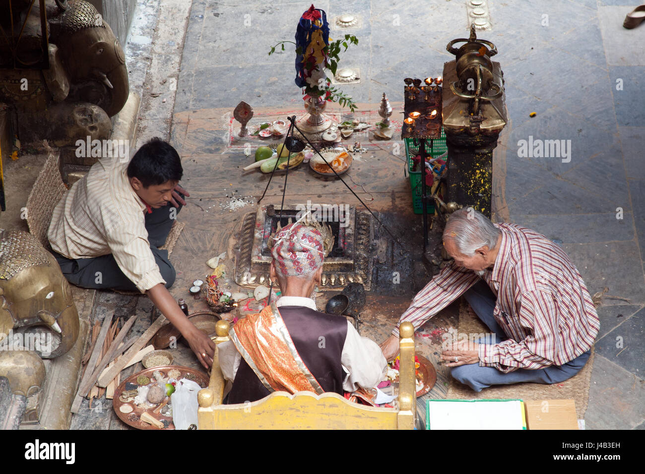 Tre uomini facendo Offerte e preghiere per il Buddha il compleanno nel Tempio d'Oro - Hiranyavarna Mahavihara - Patan, o Lalitpur, Kathmandu, Nepal Foto Stock