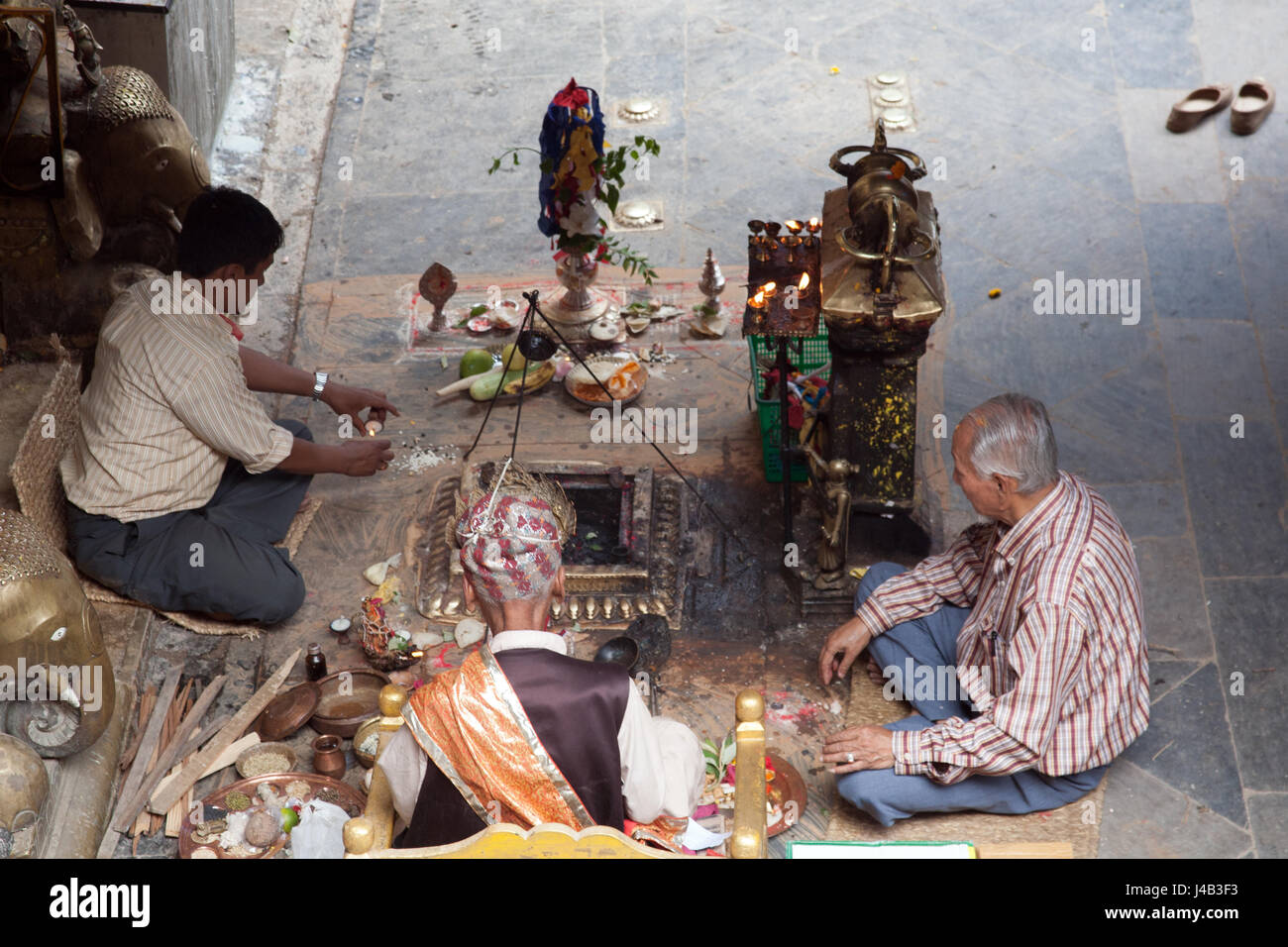 Tre uomini facendo Offerte e preghiere per il Buddha il compleanno nel Tempio d'Oro - Hiranyavarna Mahavihara - Patan, o Lalitpur, Kathmandu, Nepal Foto Stock