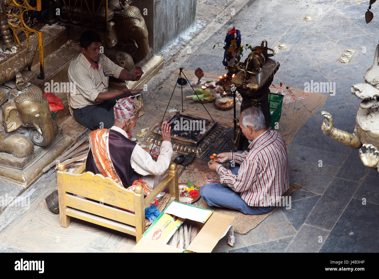 Tre uomini facendo Offerte e preghiere per il Buddha il compleanno nel Tempio d'Oro - Hiranyavarna Mahavihara - Patan, o Lalitpur, Kathmandu, Nepal Foto Stock