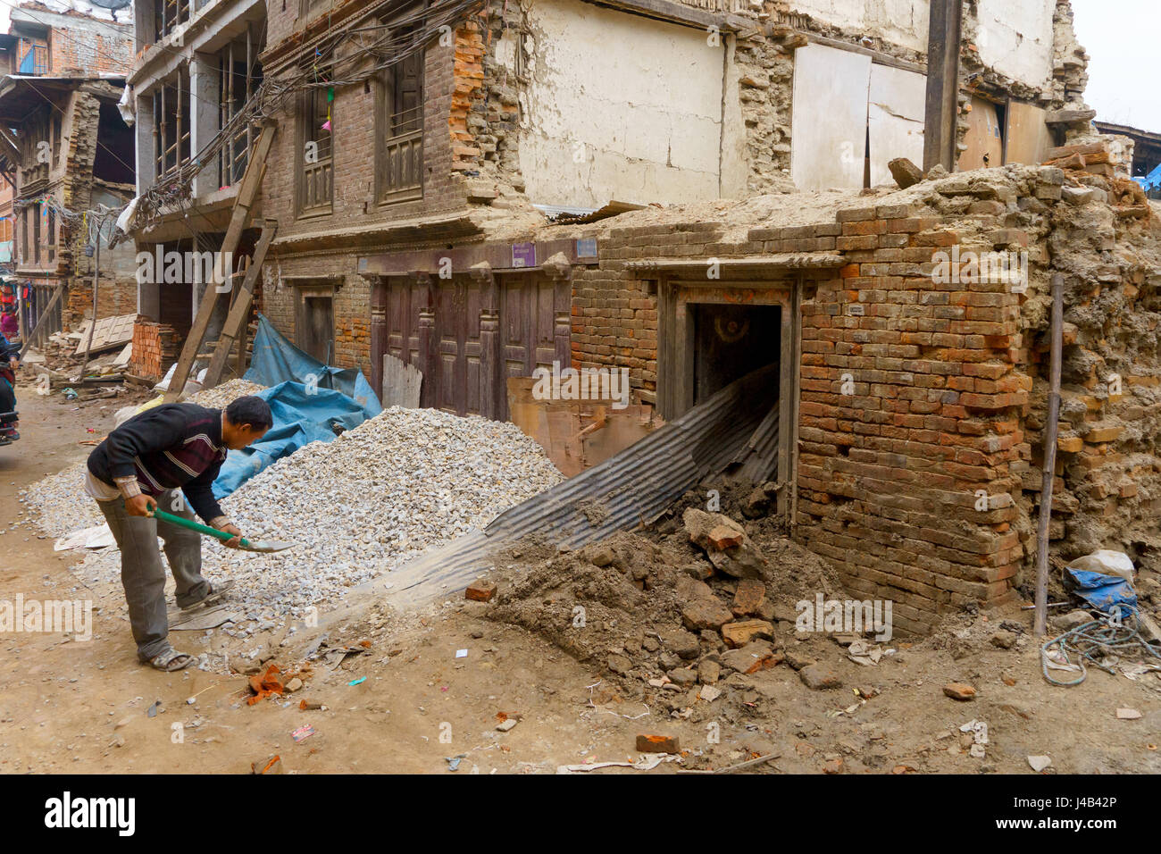 L'uomo spalare la ghiaia che saranno utilizzati per la riparazione di danni causati dal terremoto 2015 in bhaktapur, Nepal. Foto Stock