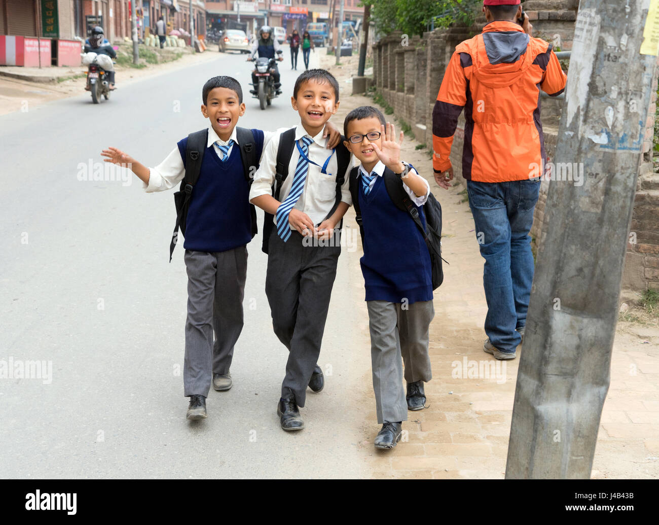 Sorridente scolari nepalese in uniformi di camminare sulla strada, Bhaktapur. Foto Stock