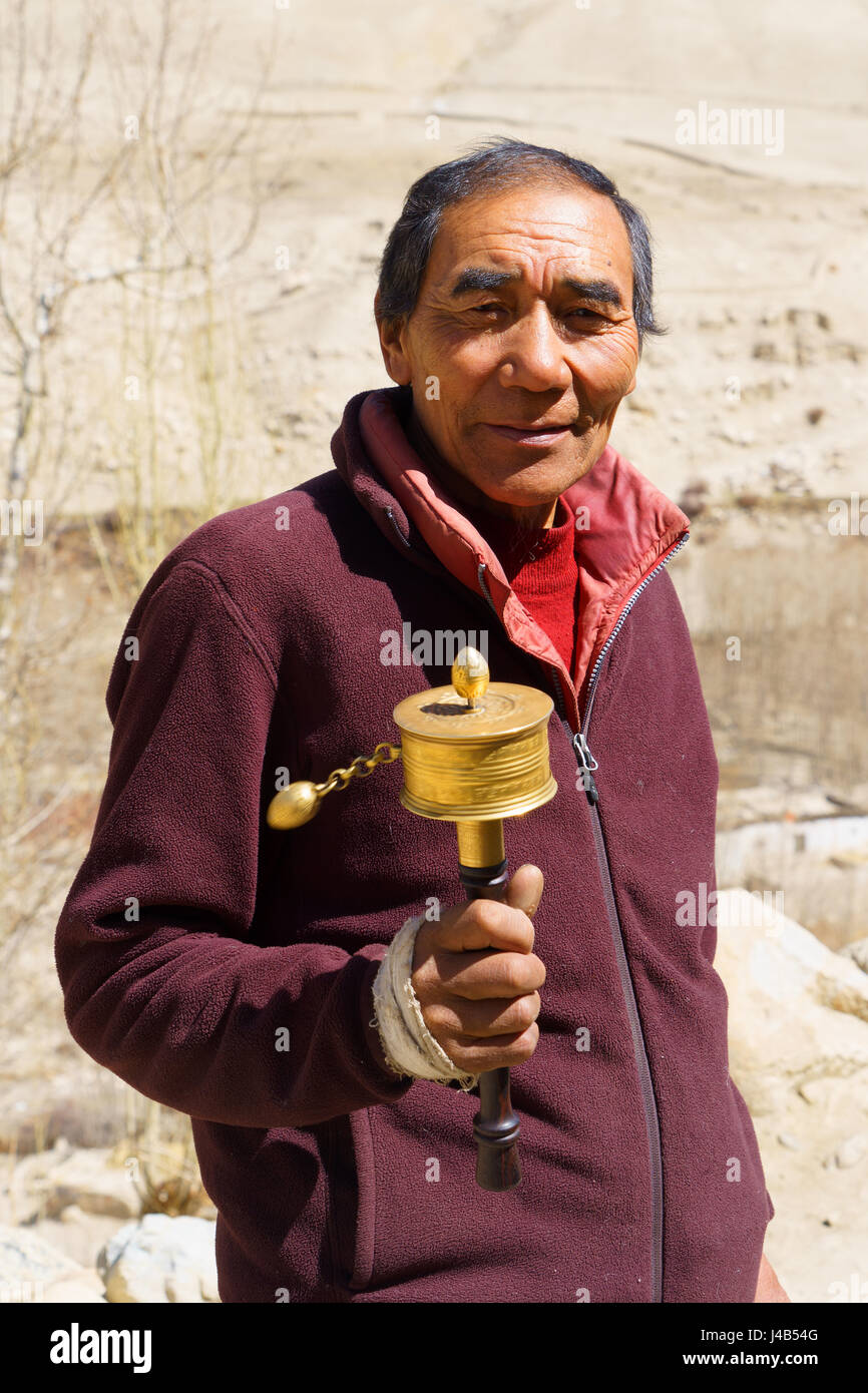 Uomo nepalese ruotando la sua preghiera ruota. Foto Stock