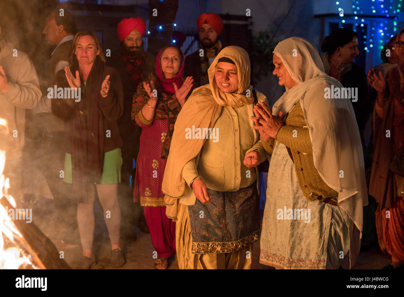 Punjabi donne preparano a gettare semi nella Lohri falò. Esso è di tipo tradizionale a gettare oggetti di piccole dimensioni nel falò, a mostrare rispetto al fuoco e natu Foto Stock