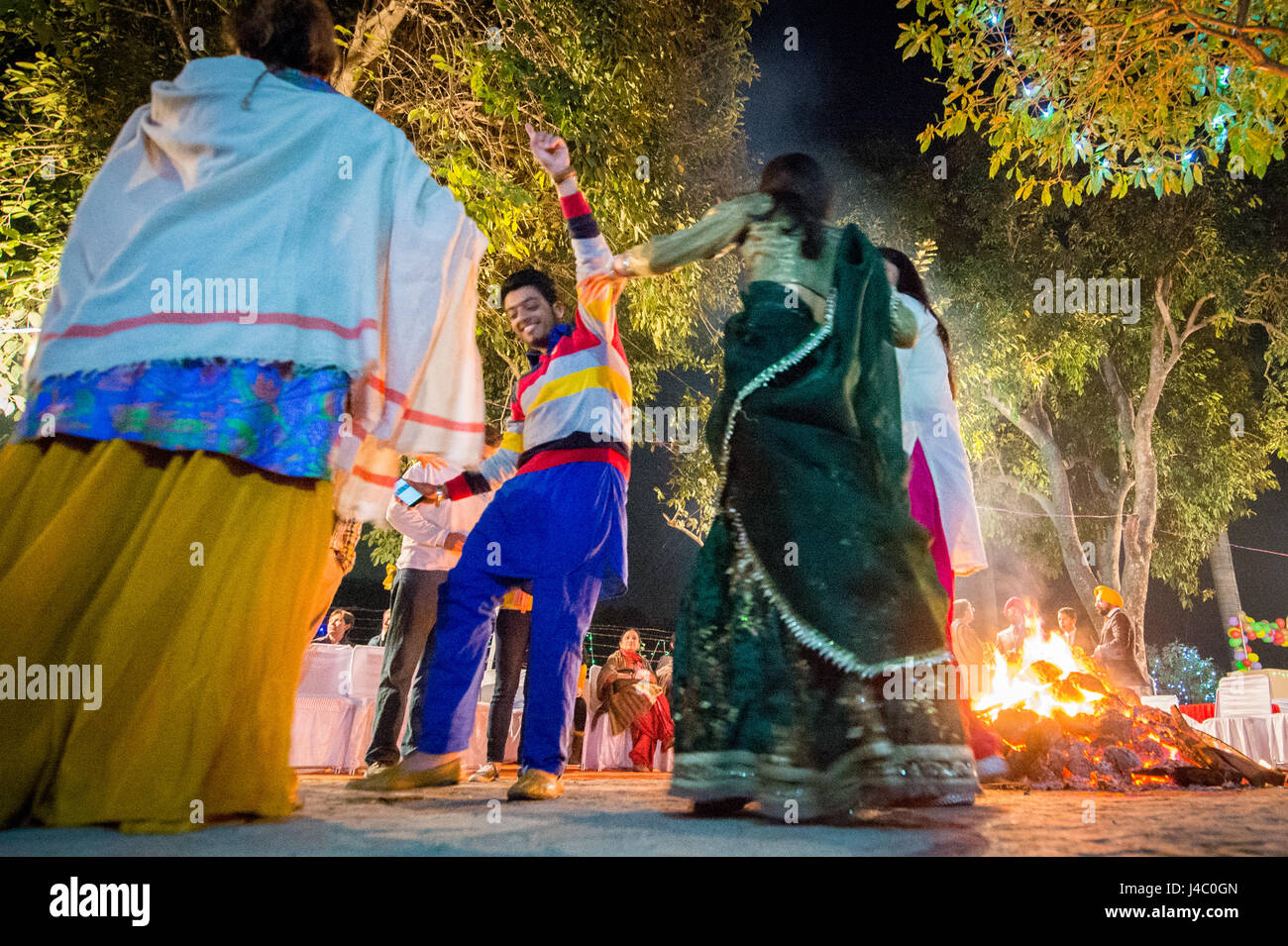 La gente ballare intorno al falò presso la celebrazione Lohri in Punjab (India). Foto Stock