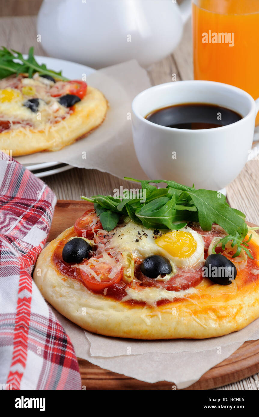 Mini pizza con salsicce e uova e rucola, una tazza di caffè Foto Stock