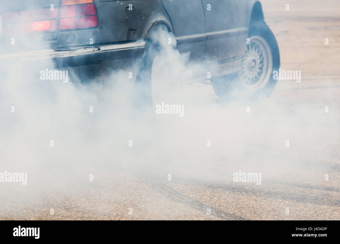 Auto dal lato con dettaglio sulla ruota di filatura, fumatori e facendo burnout pneumatico Foto Stock
