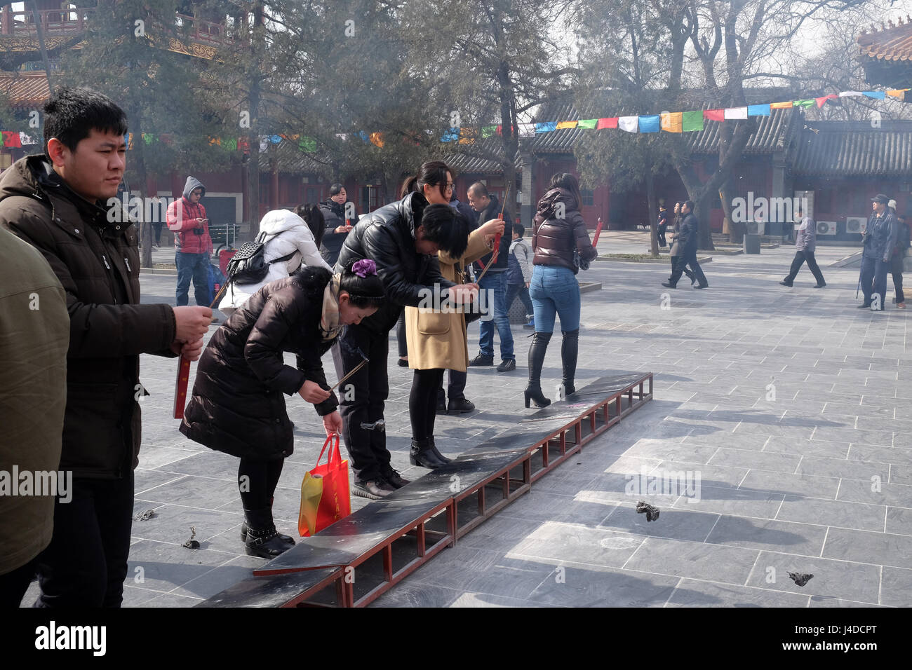 Adoratori holding bastoncini di incenso pregare presso Yonghegong il Tempio dei Lama a Pechino in Cina, 25 febbraio 2016. Foto Stock