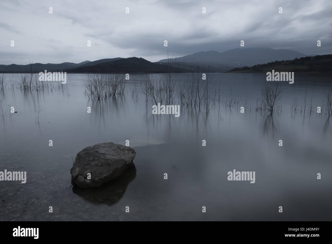 Una lunga esposizione foto di una grande roccia in un lago, sotto un cielo nuvoloso Foto Stock