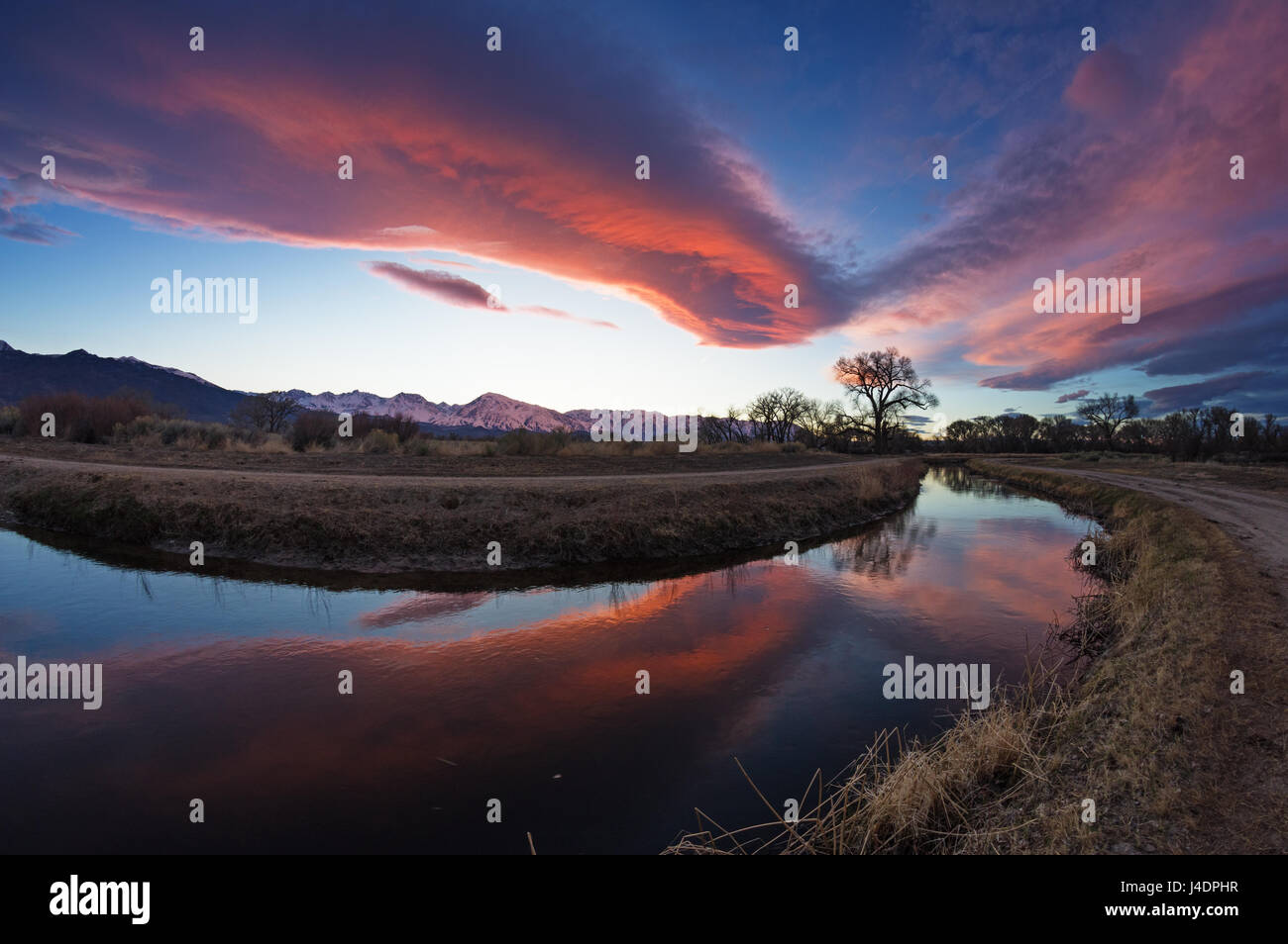 Il sierra wave cloud illuminato da un tramonto riflesso in un canale di irrigazione nella Owens Valley vicino a Vescovo California Foto Stock