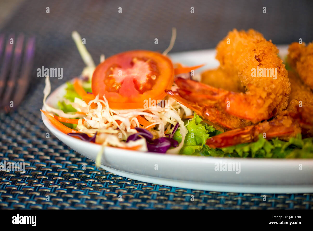 Gamberi grandi nella pastella con le verdure su una piastra da vicino Foto Stock