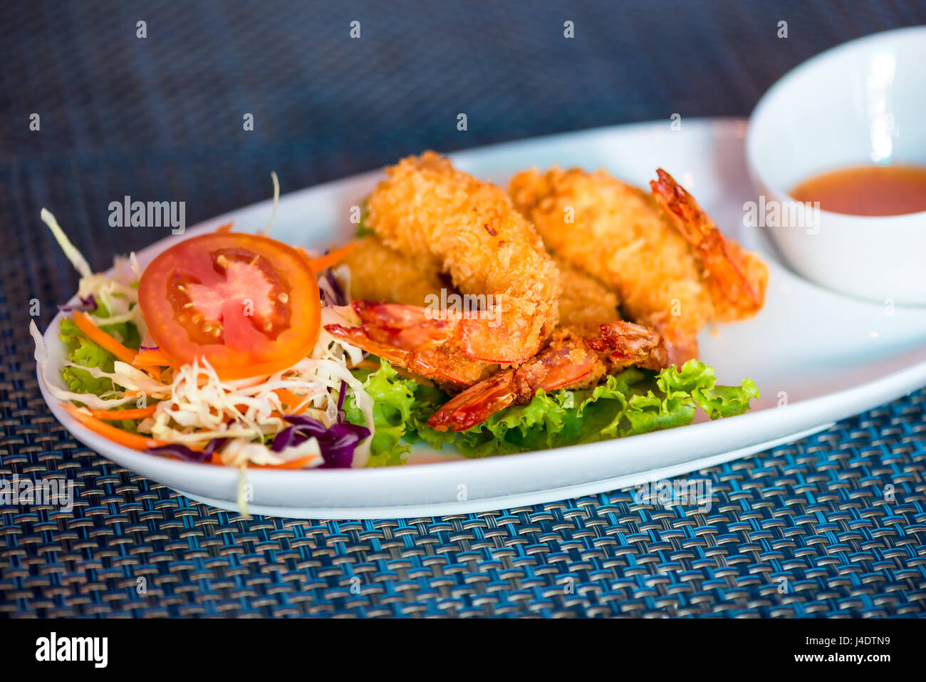 Gamberi in pastella con dolce-amaro salsa su una chiusura di piastra Foto Stock