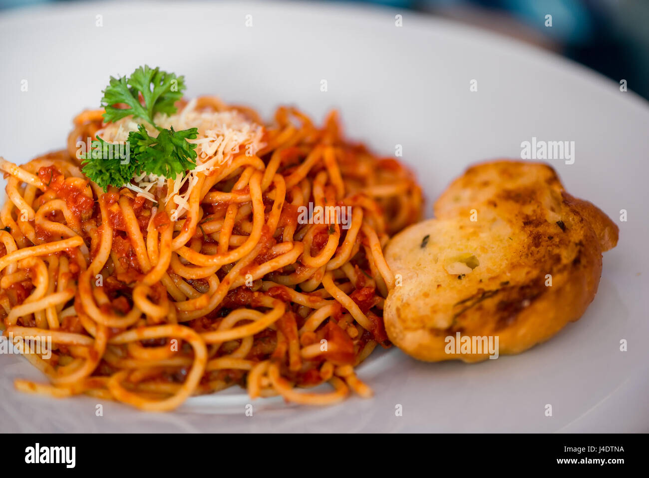 Spaghetti alla bolognese con un pezzo di fette biscottate con aglio su una piastra da vicino Foto Stock