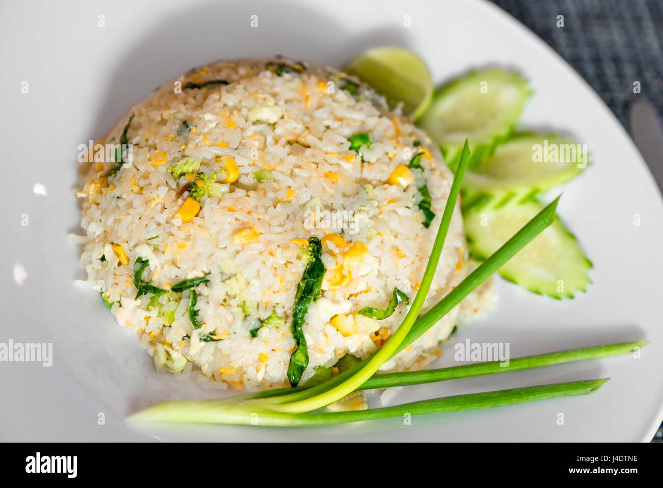 Una porzione di riso cucinato in una ricetta tailandese con verdure e uova close-up su una piastra Foto Stock
