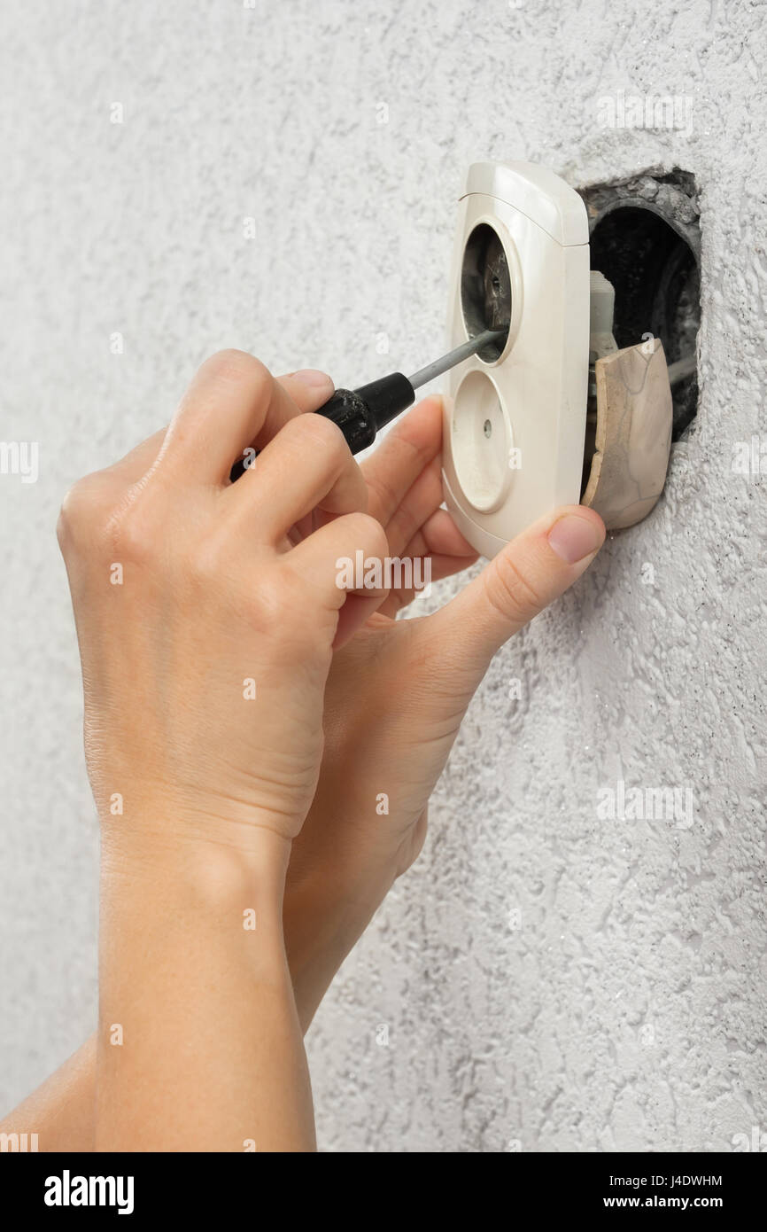 Mani di elettricista smantellamento muro rotto presa elettrica Foto Stock
