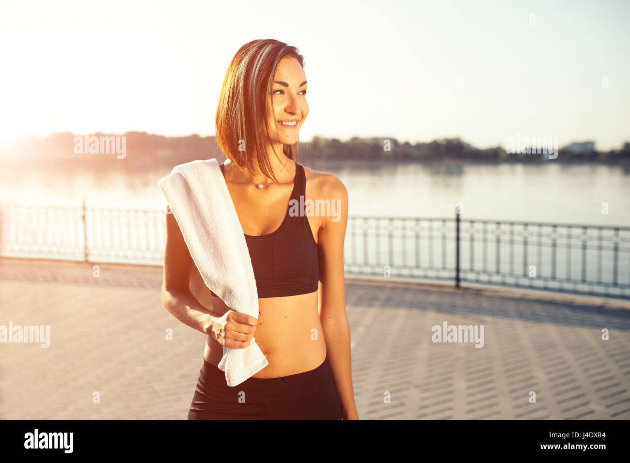 Pareggiatore sorridente donna dal lago al tramonto. Lo sport e il concetto di stile di vita Foto Stock