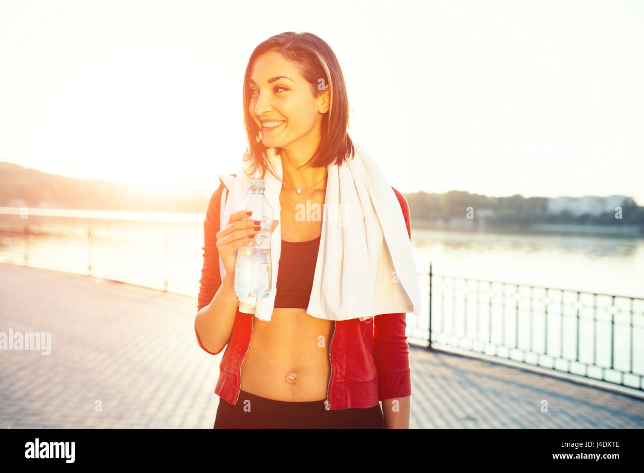 Pareggiatore sorridente donna dal lago al tramonto. Lo sport e il concetto di stile di vita Foto Stock