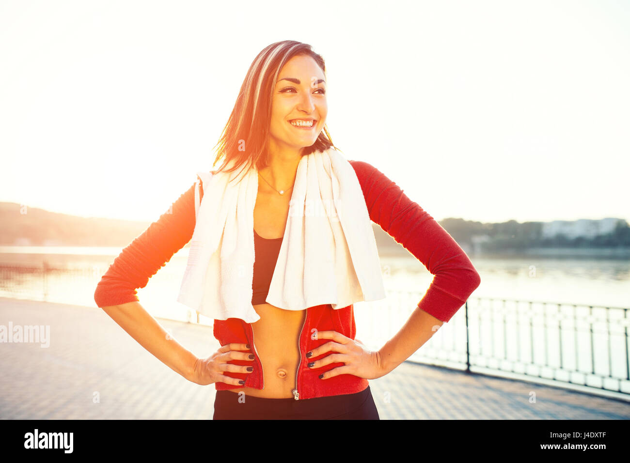 Pareggiatore sorridente donna dal lago al tramonto. Lo sport e il concetto di stile di vita Foto Stock