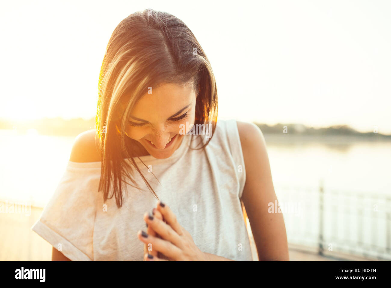Pareggiatore sorridente donna dal lago al tramonto. Lo sport e il concetto di stile di vita Foto Stock
