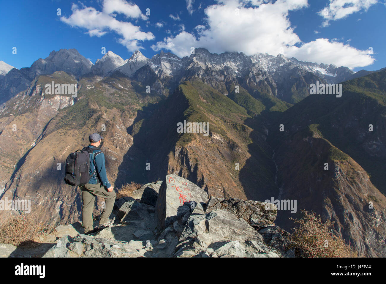 L'uomo escursionismo in Tiger che saltava Gorge, UNESCO, con Jade Dragon Snow Mountain (Yulong Xueshan), Yunnan, Cina Foto Stock