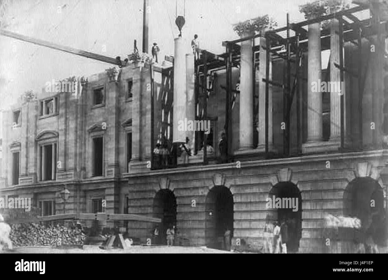 Questa immagine illustra il processo di sollevamento e allestimento di una grande colonna monolitica per l'edificio dell'Ufficio postale generale, che mostra le tecniche architettoniche utilizzate nei progetti di costruzione monumentali. Foto Stock
